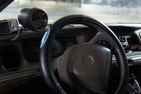2000 Mercury Grand Marquis - The interior of a 2000 Mercury Grand Marquis shows an aftermarket gauge and a Ford logo on the steering wheel cover.