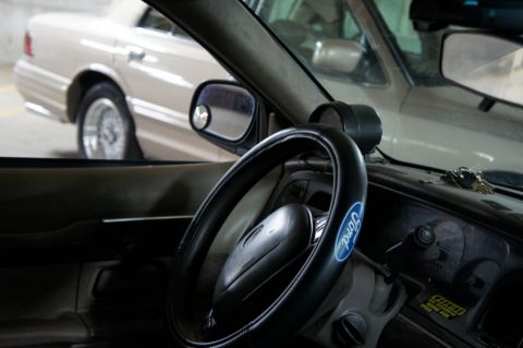 2000 Mercury Grand Marquis - The interior of a car is shown, a Ford steering wheel cover and a glimpse of another vehicle parked nearby.