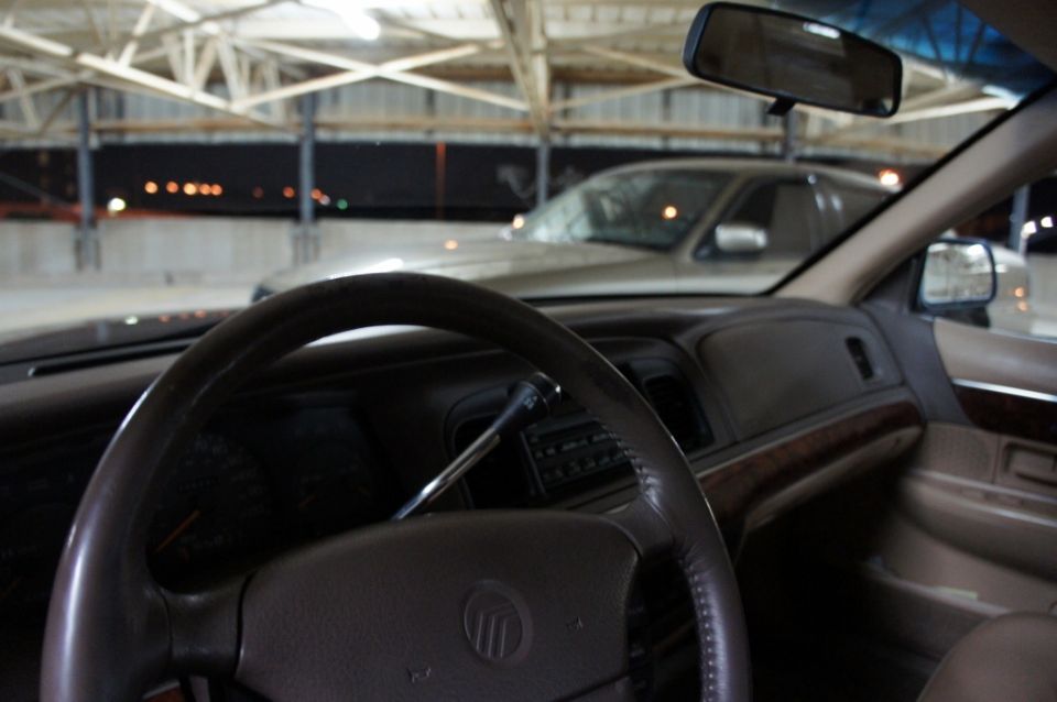 Interior shot of a 2000 Mercury Grand Marquis, looking out the windshield at another car parked nearby