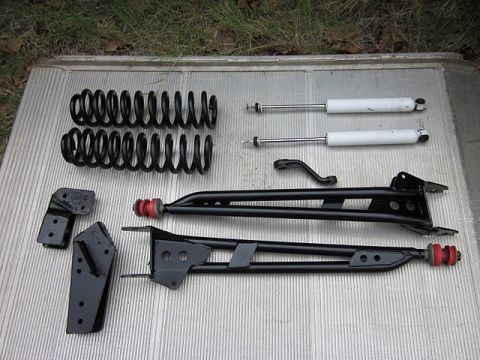 1985 Ford Bronco - A collection of suspension components, including springs, shock absorbers, and control arms, laid out on a textured surface.