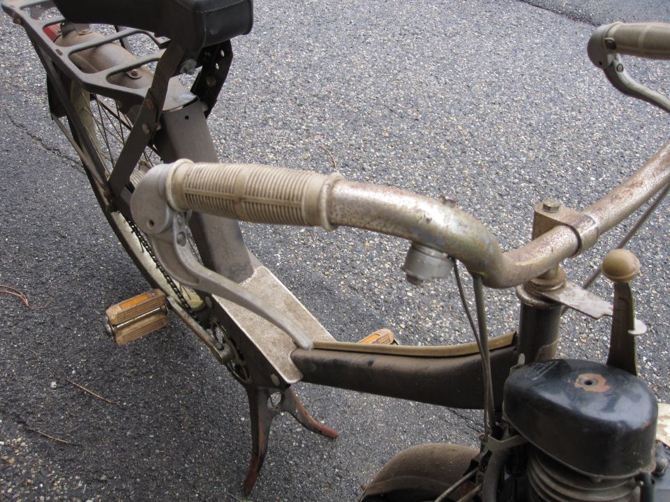 Close-up of a vintage moped's handlebars, pedals, and seat