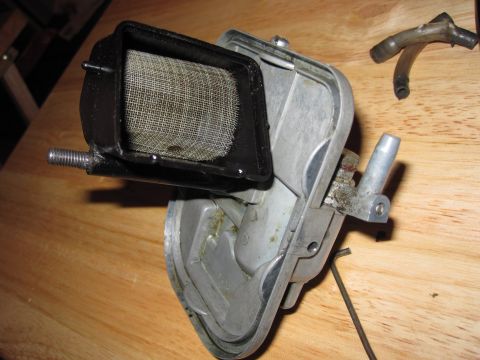 1981 Garelli Rally Sport - A disassembled motorcycle carburetor with its air filter screen is shown on a wooden table.
