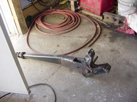 1992 Ford Bronco - A metal arm with a bracket is shown on a concrete floor, with a coiled hose in the background.