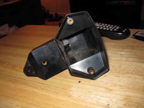 1981 Garelli Rally Sport - A black plastic component with visible brass inserts rests on a wooden table, with a remote control in the background.