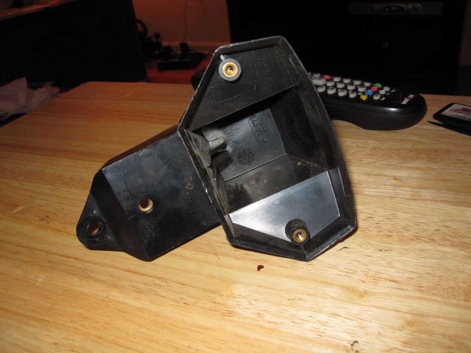 Black plastic part with brass inserts on a wooden surface