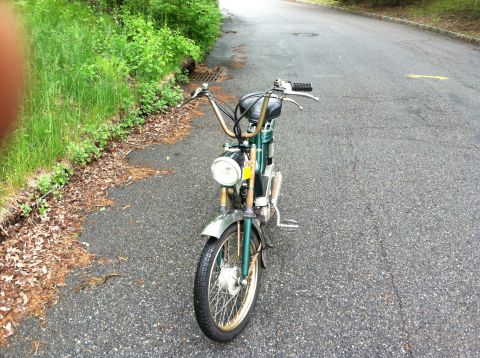 1981 Garelli Rally Sport - A green moped with chrome accents is parked on an asphalt road next to a grassy embankment.