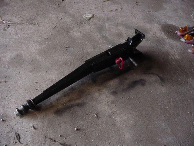Black metal jack with red handle and threaded screw base on concrete floor