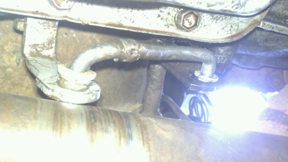 close up of a metal brake line running under a vehicle, attached with a bracket
