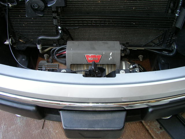 Silver truck front bumper with a WARN winch mounted behind the grille