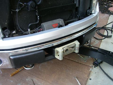 1995 Ford Bronco - Close-up of a front bumper assembly a winch and tow hooks, with the grille and radiator visible behind.
