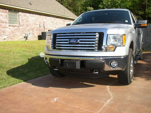 1995 Ford Bronco - Front view of a silver Ford F-150 truck, a chrome grille with horizontal bars and a central Ford emblem.