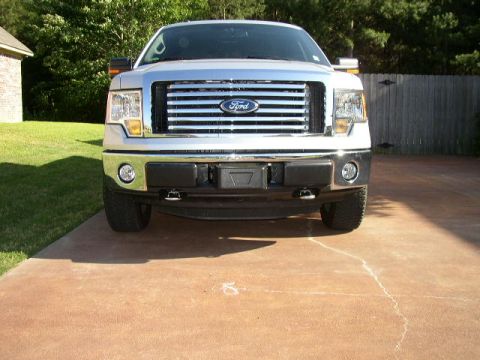 1995 Ford Bronco - This Ford F-150 truck is parked on a concrete driveway in front of a wooden fence.