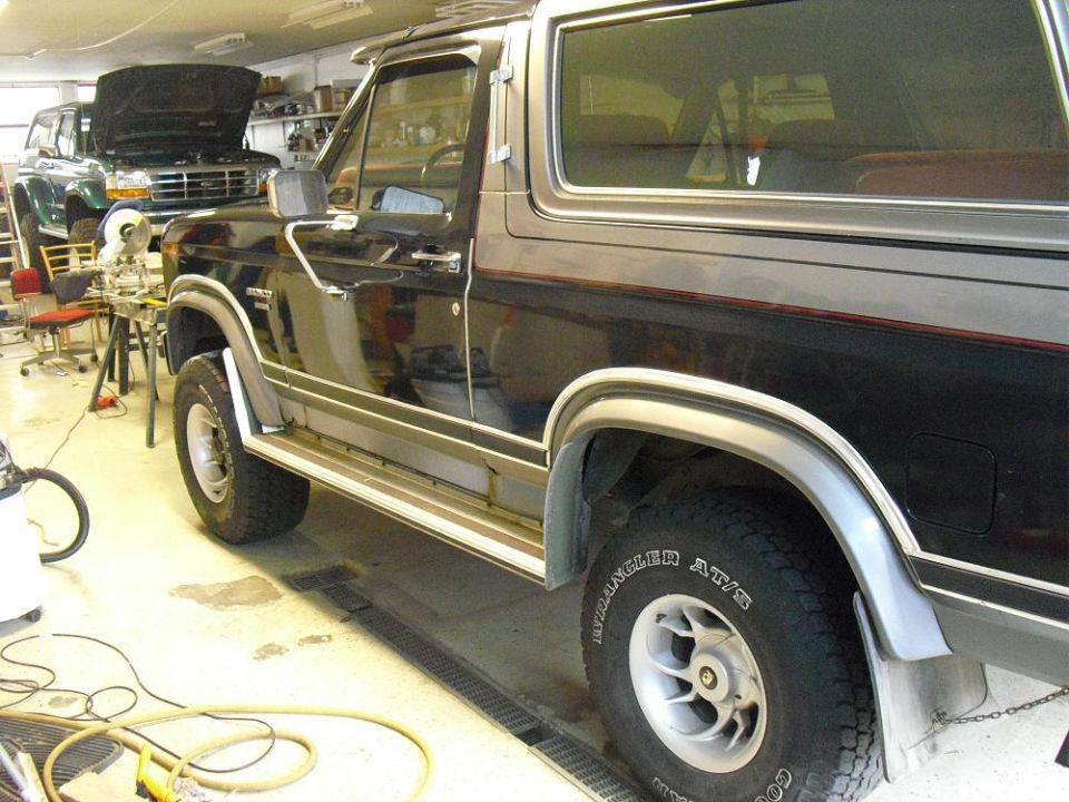 Black and silver Ford Bronco SUV in profile inside a garage shop