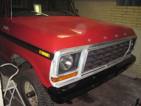 1979 Ford Bronco - The front of a red 1979 Ford Bronco is visible, showing its grille and hood.