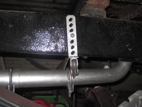1979 Ford Bronco - Underside view of a vehicle's exhaust system and frame, showing a metal bracket securing the pipe.