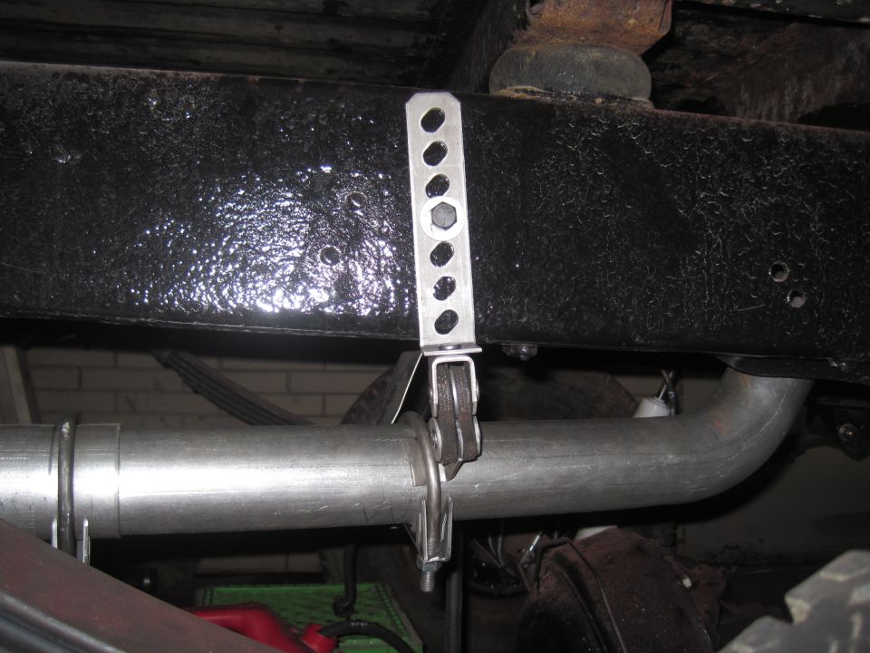 Close-up of exhaust pipe attached to vehicle frame with a metal bracket