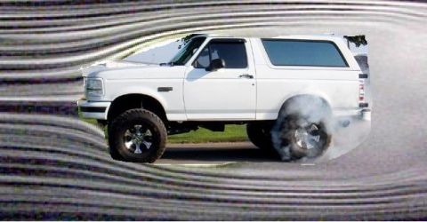 1989 Ford Bronco - A white Ford Bronco performs a burnout, kicking up smoke from its rear tire.