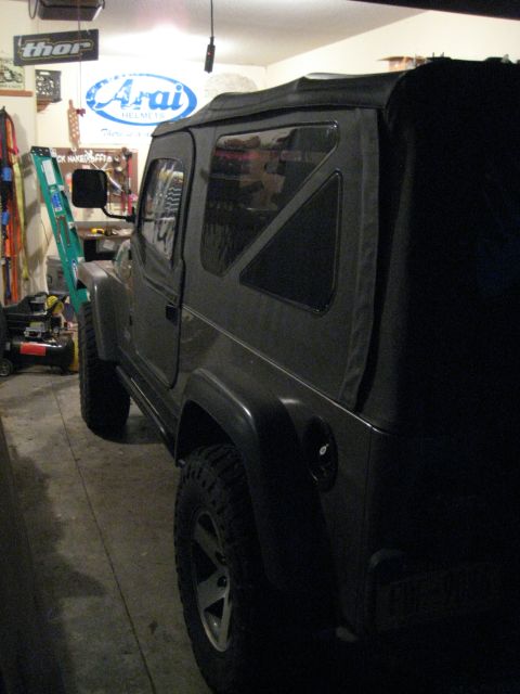 2005 Jeep Wrangler - A Jeep Wrangler is parked inside a garage, with tools and a ladder visible in the background.