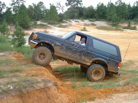 1995 Ford Bronco - A driver navigates a muddy off-road course in a lifted Ford Bronco.
