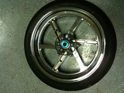 1996 Ford Bronco - Chrome motorcycle wheel with six spokes and a blue center cap is shown on a speckled floor.