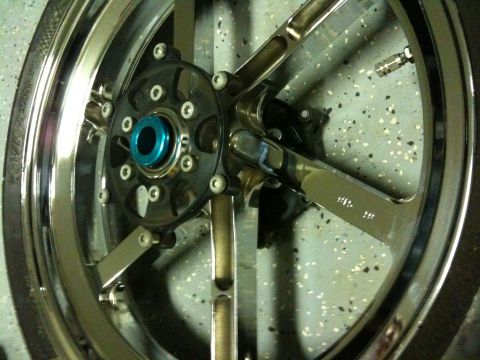 1996 Ford Bronco - A close-up view of a custom chrome motorcycle wheel with a blue center hub and black spokes.