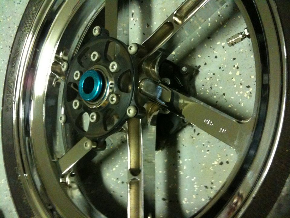 Chrome custom motorcycle wheel with blue hub and black spokes, close-up