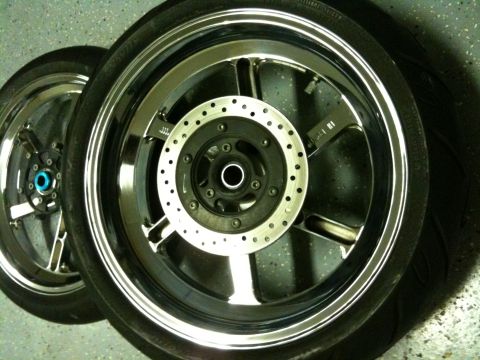 1996 Ford Bronco - Close-up view of two motorcycle wheels, each a chrome rim and a perforated disc brake assembly.