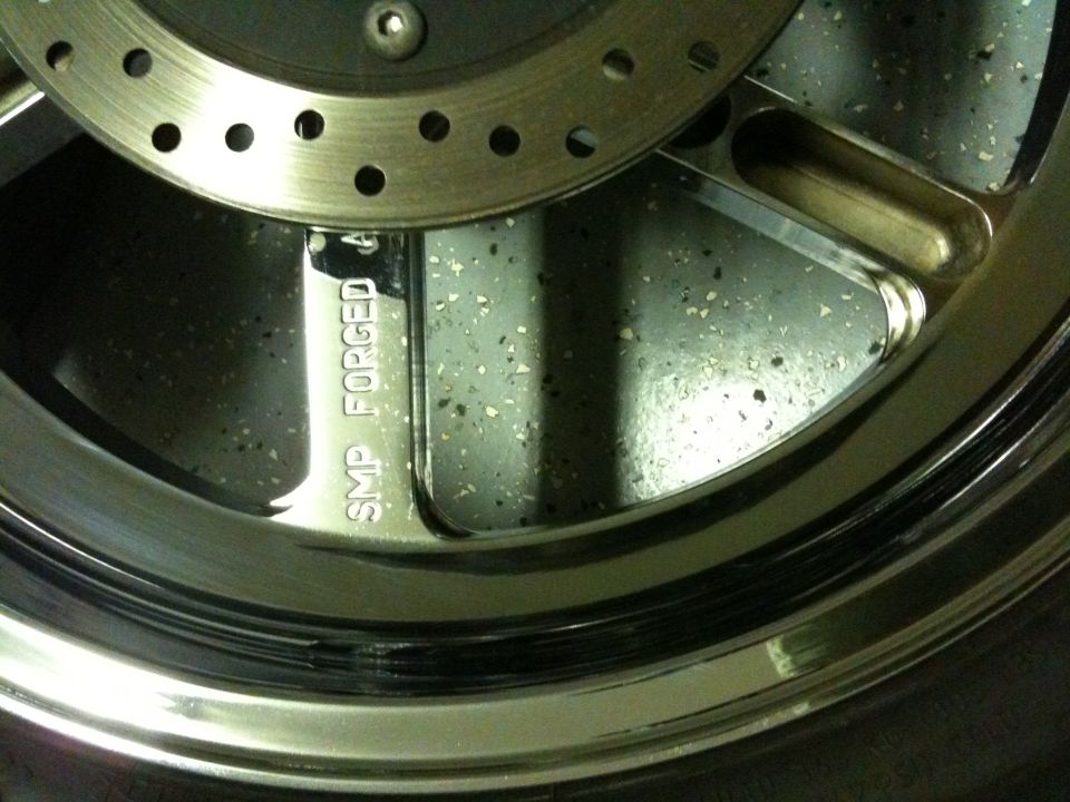 Close-up of a chrome wheel with 'SMP FORGED' text and a brake rotor