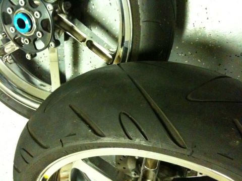 1996 Ford Bronco - Two motorcycle tires are shown, with one partially obscuring the other. The rear tire is in focus, highlighting its tread pattern.