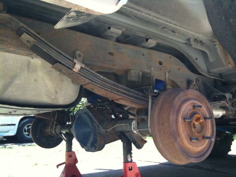 1996 Ford Bronco - Underside view of a 1996 Ford Bronco's rear suspension and axle assembly, supported by jack stands.