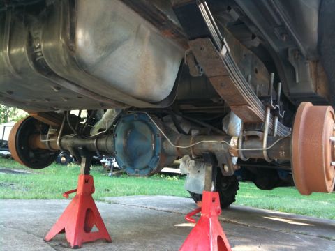 1996 Ford Bronco - Underside view of a 1996 Ford Bronco's rear axle and suspension system, supported by red jack stands.