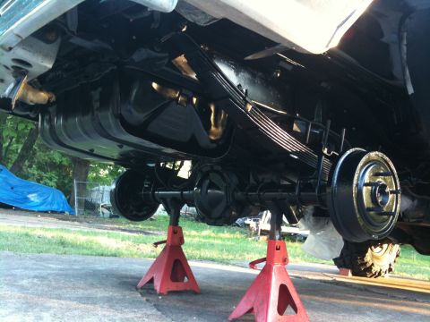 1996 Ford Bronco - Vehicle's rear axle and fuel tank are visible while it's elevated on jack stands for maintenance.