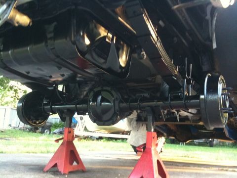 1996 Ford Bronco - The rear axle and fuel tank of a vehicle are visible, supported by red jack stands.
