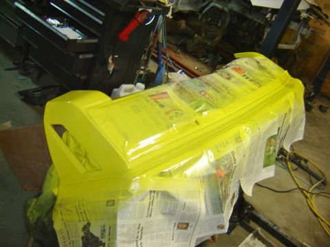 1979 Ford Mustang - A car part is being painted yellow, covered with newspaper and masking tape.