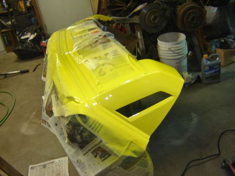1979 Ford Mustang - A yellow car part, covered in masking tape, is being prepped for painting in a garage setting.
