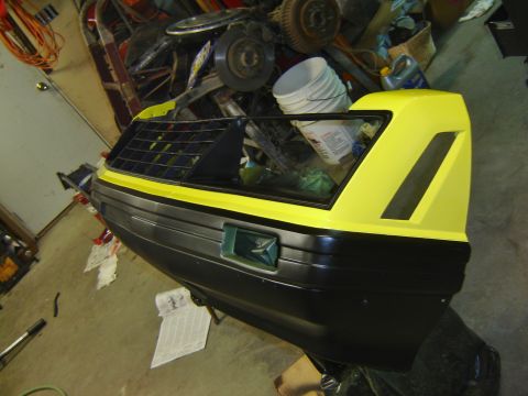 1979 Ford Mustang - A car bumper and rear quarter panel, painted black and yellow, sits in a cluttered garage.