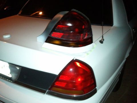 1998 Ford Crown Victoria - Night close-up of the rear corner of a white Ford Crown Victoria, showing the installed red tail light lens in the quarter panel and a seco…