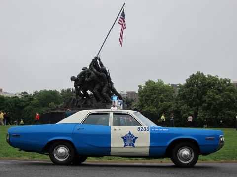 1991 Ford LTD Crown Victoria - blue-and-white police sedan numbered 8208 parked on grass in front of the Iwo Jima Marine Corps War Memorial statue.