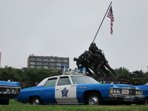 1991 Ford LTD Crown Victoria - blue-and-white classic police cruiser marked 9559 with a star emblem parked on grass before the Iwo Jima Memorial.