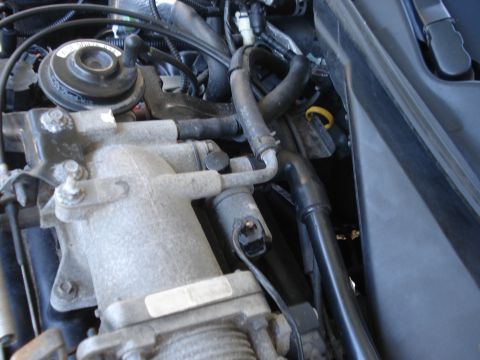 2000 Ford Crown Victoria - Close-up view of engine components, including hoses and electrical connectors, within a vehicle's engine bay.