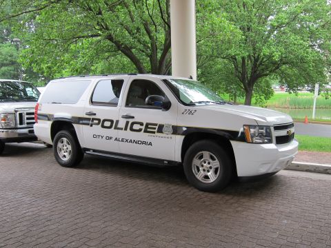 1991 Ford LTD Crown Victoria - Front quarter view of a white Chevrolet Suburban marked POLICE City of Alexandria parked on a brick driveway.