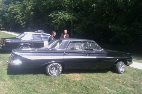1991 Ford LTD Crown Victoria - A classic black Chevrolet Impala with chrome trim sits on grass next to a police car.