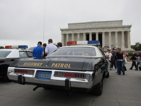 1991 Ford LTD Crown Victoria - People gather around a black-and-white Dodge marked HIGHWAY PATROL parked before the columned Lincoln Memorial.