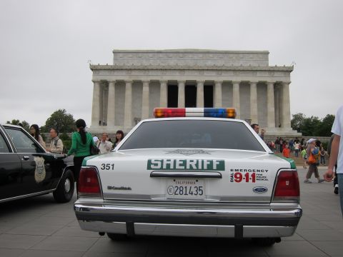 1991 Ford LTD Crown Victoria - rear of a white-and-green Ford Crown Victoria marked SHERIFF with California plates sits before the Lincoln Memorial.