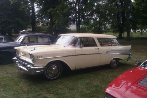 1991 Ford LTD Crown Victoria - A cream and silver 1957 Chevrolet Nomad station wagon is parked outdoors with other vehicles.