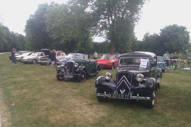 Black Citroën Traction Avant with license plate 327 EZF 77 parked on grass with other vintage cars