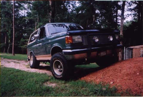 1989 Ford Bronco - This green SUV, possibly a 1987 model, is shown in a 3/4 front view on a dirt mound. The license plate is visible.