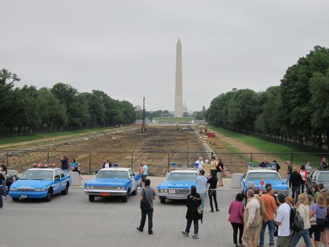 1991 Ford LTD Crown Victoria - row of blue vintage police cars lined up on a plaza facing the Washington Monument and the drained reflecting pool.