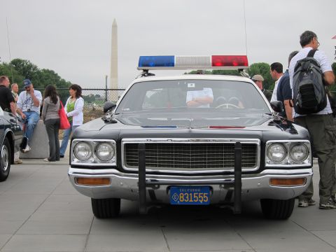 1991 Ford LTD Crown Victoria - Front view of a dark Dodge police cruiser fitted with a push bumper and California plate, Washington Monument in the haze.