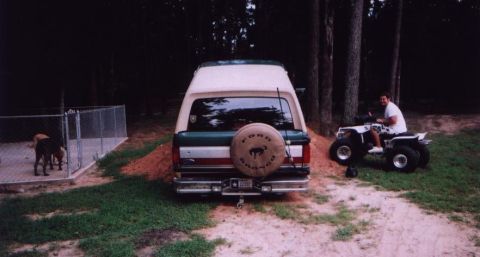 1989 Ford Bronco - 1989 Ford Bronco with spare tire cover, parked outdoors with an ATV and dogs nearby.